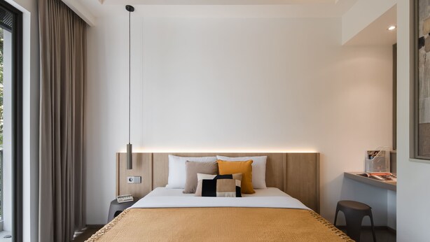 A modern hotel room with a large bed, a bedside table, a desk, and a chair. - Cove Svasa (Jakarta)