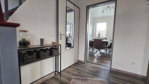 A hallway with a wooden floor, a mirror, a small table with a candle and a plant, and a rug. - Relax by the Water – Vacation Home with Its Own Boat Dock in Emden (Emden)