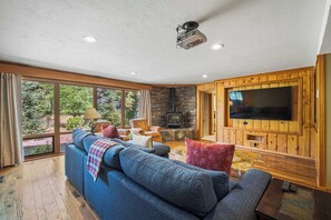 A living room with a large television, a stone fireplace, and a blue sofa. - S7610 | 10 Deschutes (Sunriver)