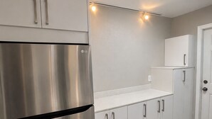 Una cocina moderna con electrodomésticos de acero inoxidable, armarios blancos e iluminación debajo de los gabinetes.