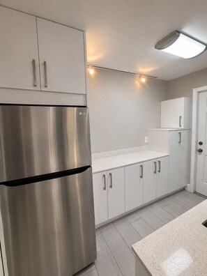 A modern kitchen with stainless steel appliances, white cabinetry, and under-cabinet lighting.