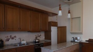 Una cocina con armarios de madera, encimeras de granito, un refrigerador y lámparas colgantes.