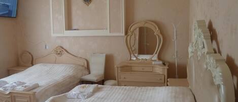 Habitación de hotel con dos camas, un tocador con espejo, un reloj de pared y una televisión.