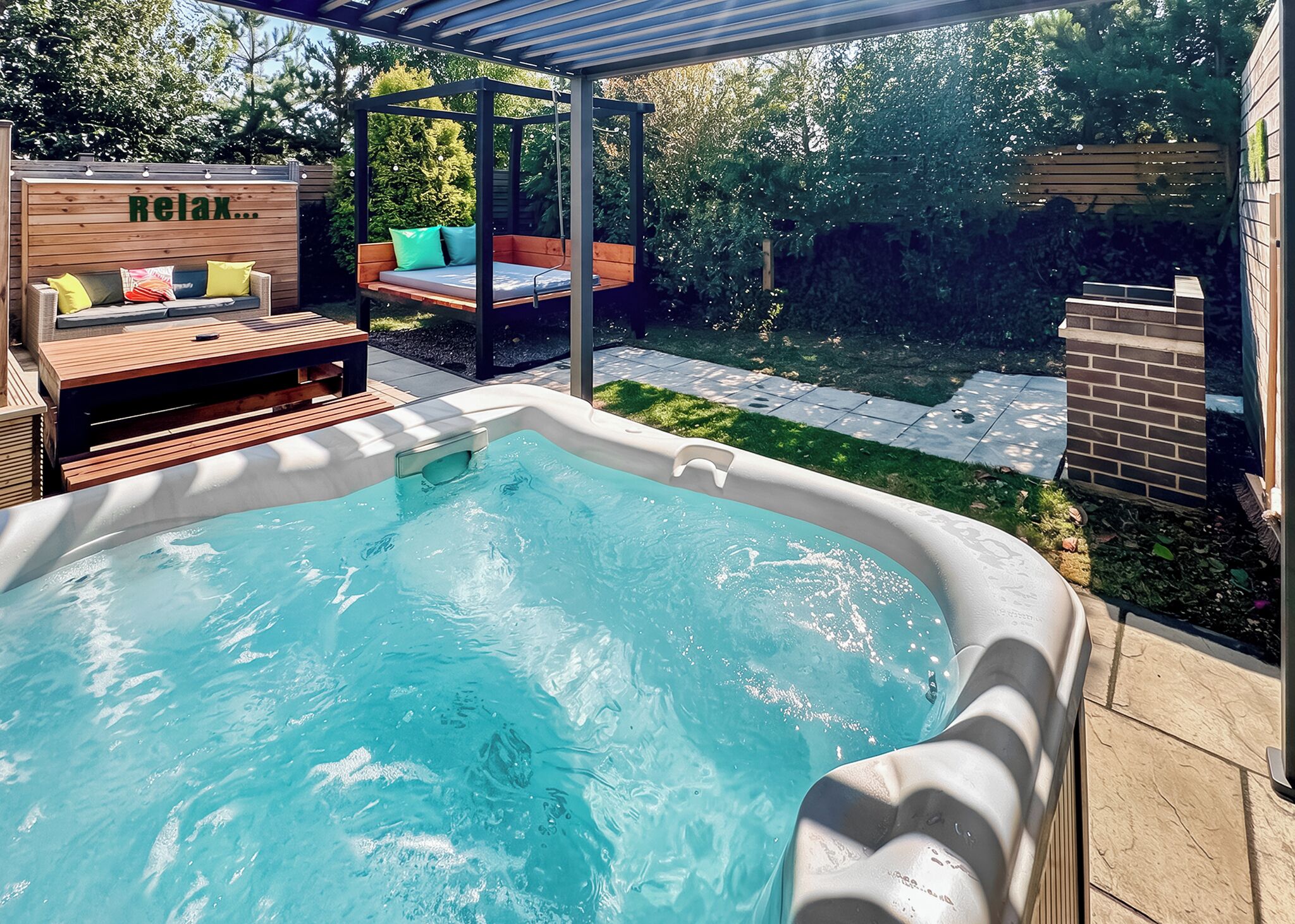 A backyard with a hot tub, wooden deck, and outdoor seating area.