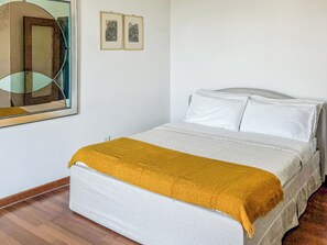 Quarto com uma cama, um espelho e duas quadros na parede.
