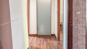 A hallway with a wooden floor, a door with frosted glass, and a framed picture on the wall. - Maison Panorama (Perugia)