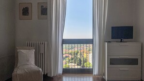 A room with a bed, a radiator, a TV on a cabinet, and a window with curtains. - Maison Panorama (Perugia)