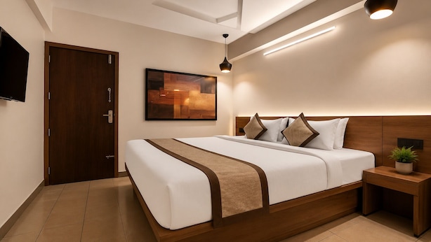 Una habitación de hotel moderna con un marco de cama de madera, un televisor de pantalla plana, una mesita de noche con una planta y una obra de arte colgada en la pared.