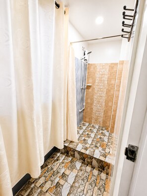 Une salle de bain avec une douche, des murs carrelés et un sol à motifs.