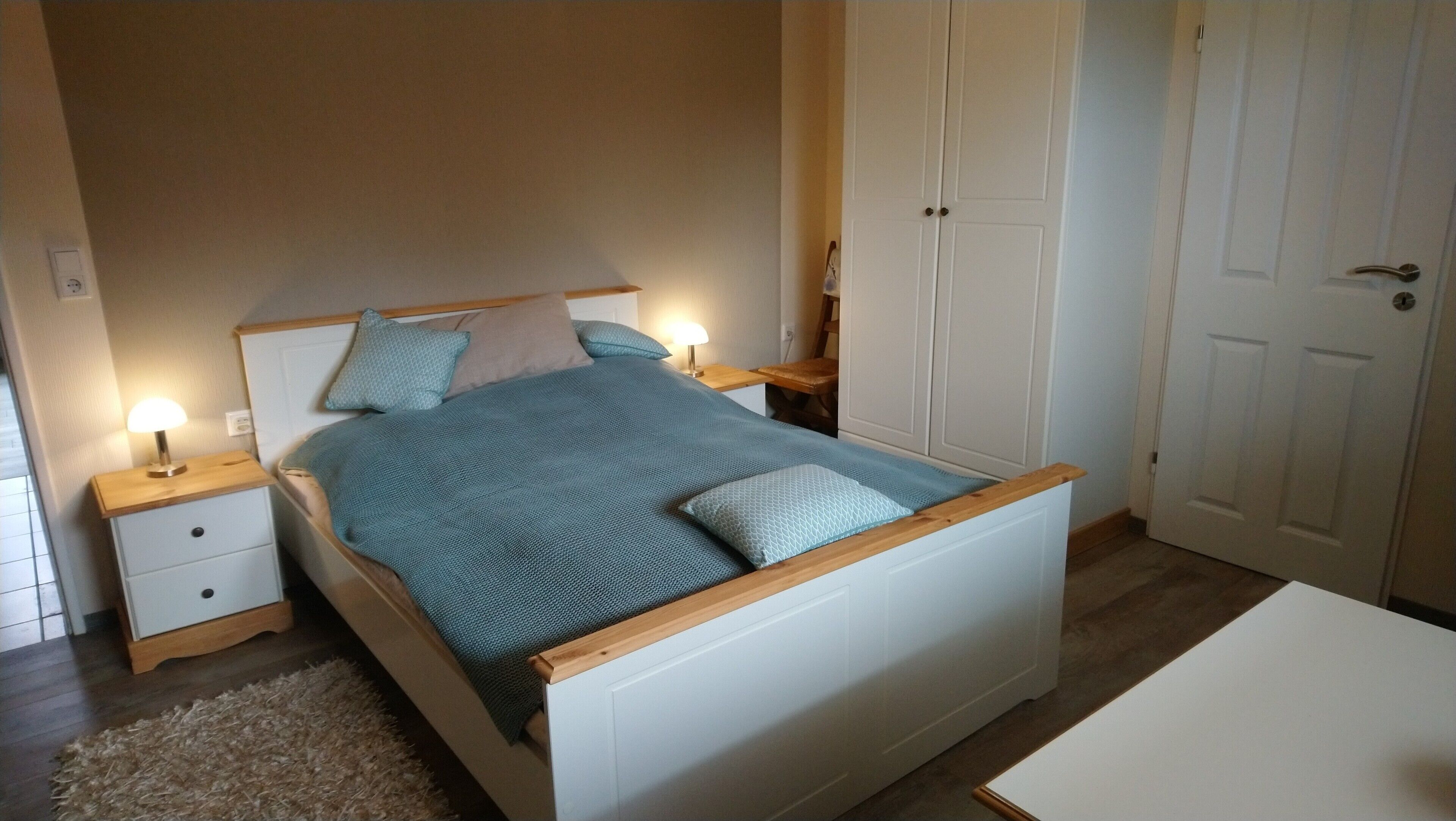 Ein Schlafzimmer mit einem Bett, Nachttischen, einem kleinen Tisch und einem Stuhl.