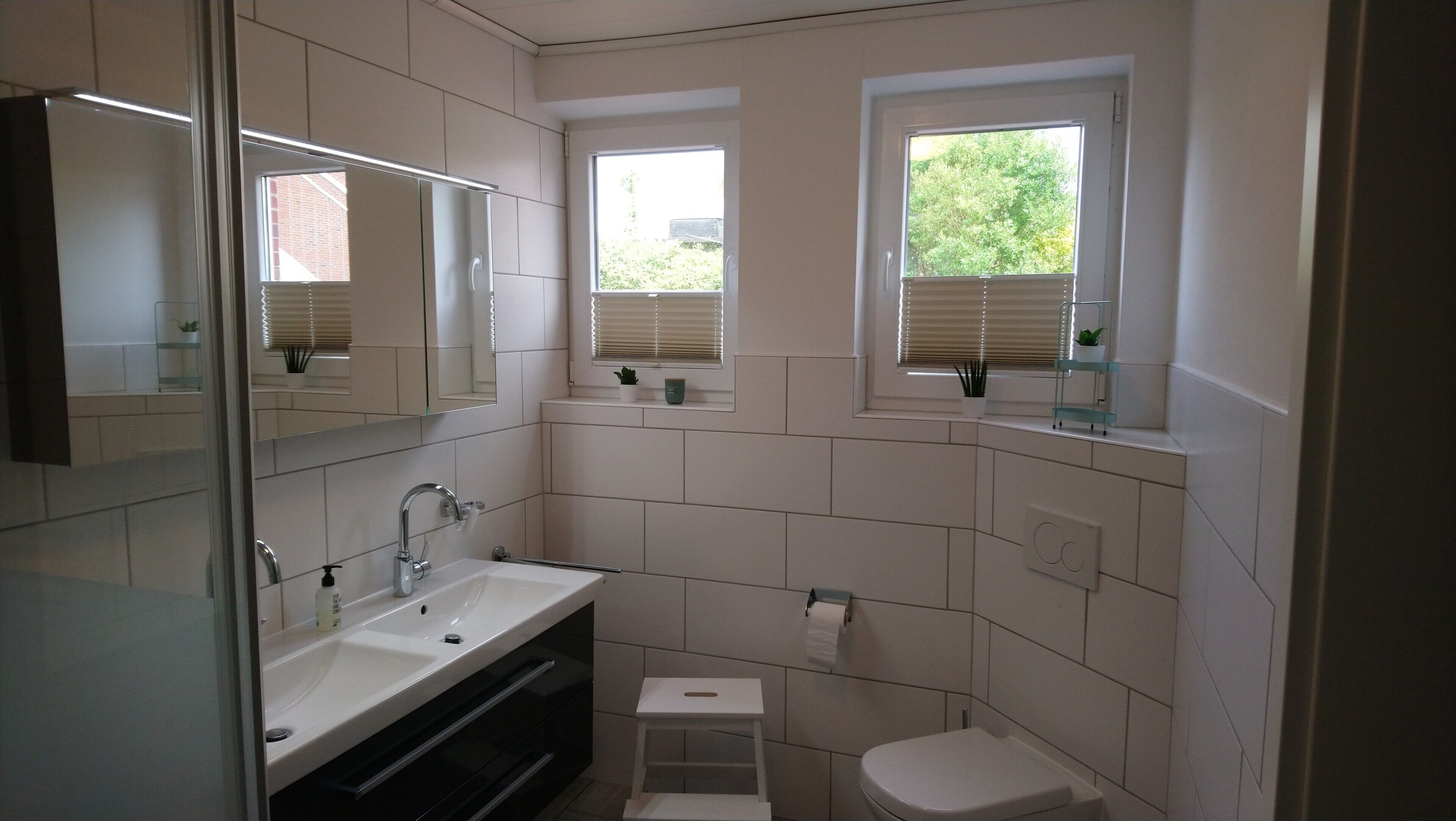 Ein modernes Badezimmer mit Duschkabine aus Glas, einem weißen Waschbecken und einer Toilette.