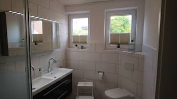Ein modernes Badezimmer mit Duschkabine aus Glas, einem weißen Waschbecken und einer Toilette.
