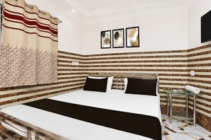 Habitació d'hotel amb un llit, una taula auxiliar i televisió penjada a la paret.