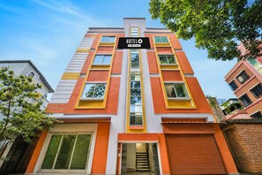 Hotel de diversos pisos amb un senyal ben visible que diu 'HOTELO', disseny arquitectònic modern amb accents de color taronja i blanc.