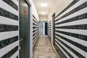 Un pasillo con puertas numeradas 10 y 09, que conduce a una habitación con piso de mármol.