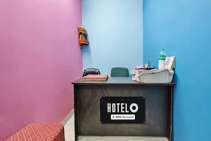 Un taulell de recepció amb un cartell que diu 'HOTELO OYO-Serviced' en una habitació amb parets roses i blaves.