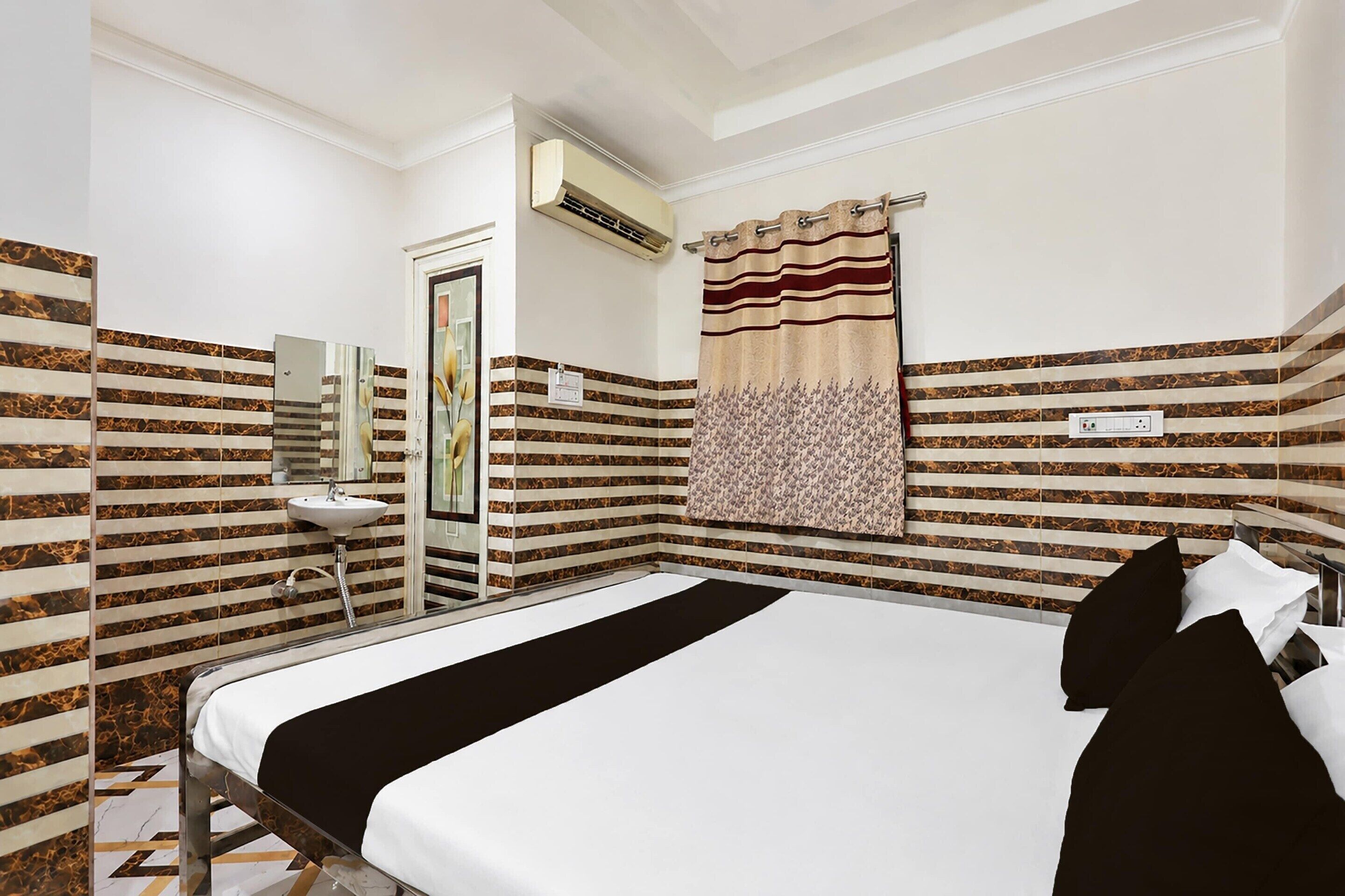 A hotel room with a bed, a bathroom with a sink, and a shower.