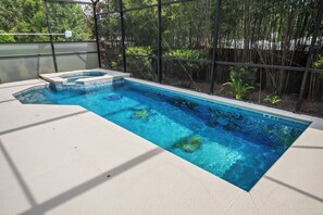Ein rechteckiger Swimmingpool mit Whirlpool, umgeben von einem Bambuszaun und einer Betonplattform.