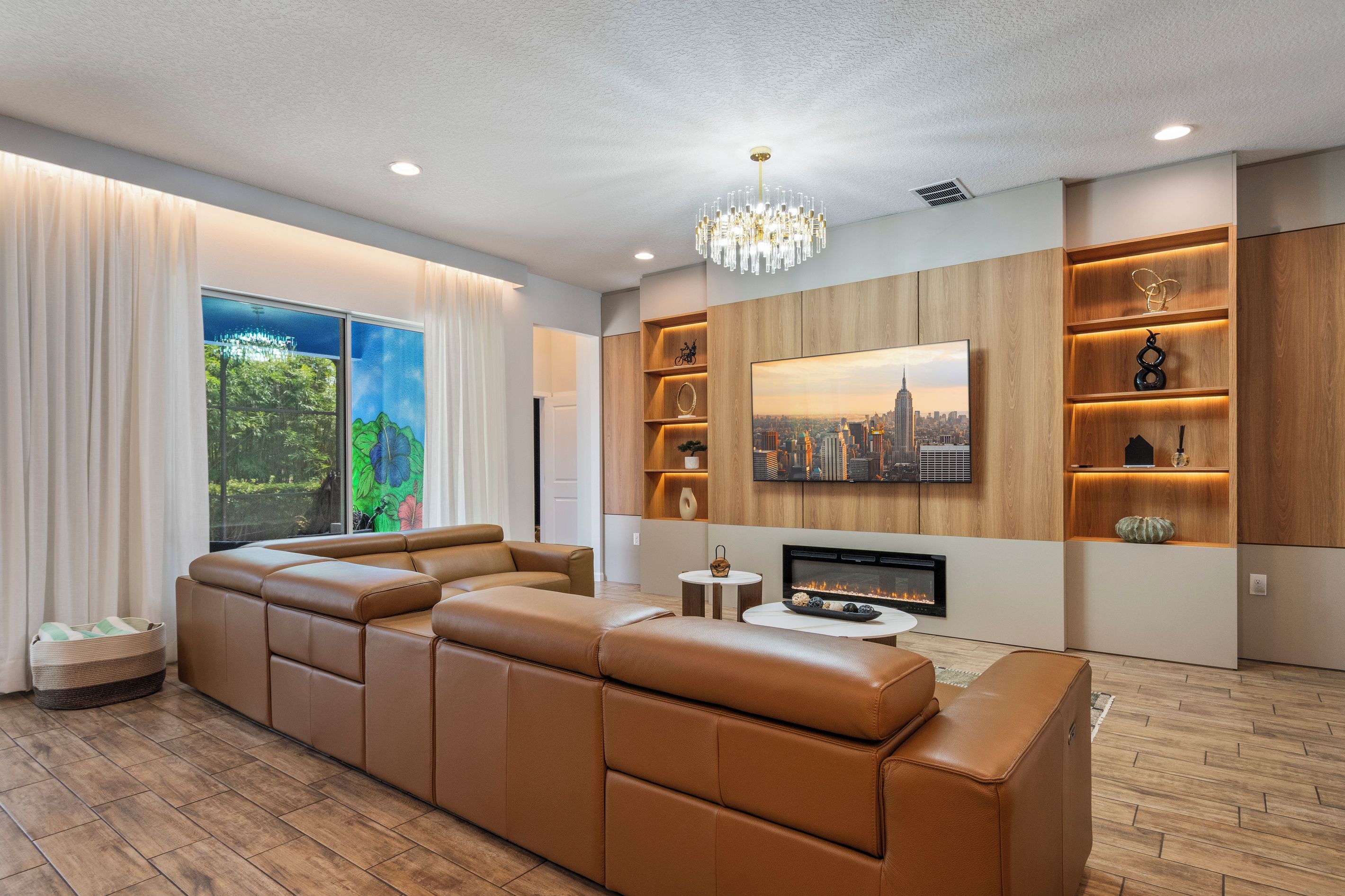A modern living room with a sectional sofa, a fireplace, and a large window with a cityscape view.