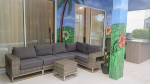 A sectional sofa with a matching ottoman, a small table, and a potted plant. - Luxury Disney Manson - Newly renovated - Sleeps 30+ - Book today (Kissimmee)