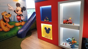 A children's play area with a slide, cartoon character murals, and shelves with toys. - Luxury Disney Manson - Newly renovated - Sleeps 30+ - Book today (Kissimmee)