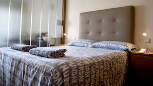 A neatly made bed with patterned bedding, a headboard, and a bedside table with a lamp. - Vacation Studio 'Terraza A La Playa' with Wi-Fi (Las Palmas de Gran Canaria)