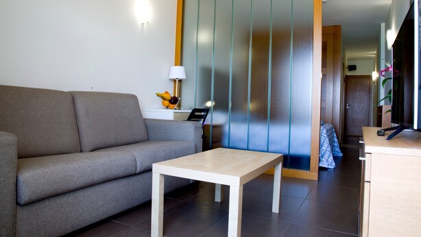 A modern living room with a sofa, a small table, and a decorative lamp. - Vacation Studio 'Terraza A La Playa' with Wi-Fi (Las Palmas de Gran Canaria)