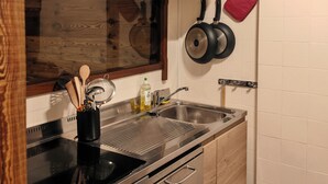 A modern kitchen with wooden cabinets, stainless steel appliances, and a hanging pot rack. - Apartment at the foot of the legendary Matterhorn in the Cervina–Zermatt area. (Breuil-Cervinia)