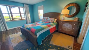 Een slaapkamer met een bed, een dressoir, een spiegel en een raam.