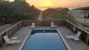 A swimming pool with lounge chairs and a view of the beach at sunset. - Spectacular Sunrises, Pool, Hot Tub, Theater Room, Office, SN9317 (Nags Head)