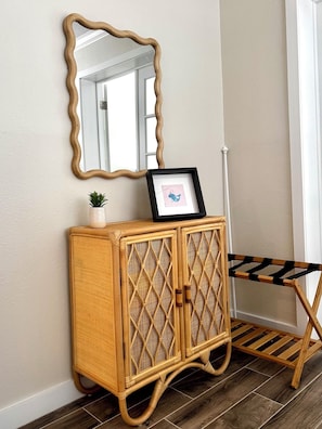 A corner with a woven rattan cabinet, a framed picture, and a wooden chair. - 2 BDR 1st floor Poolside Condo overlooking Intercoastal & STEPS to beach! (Indian Shores)