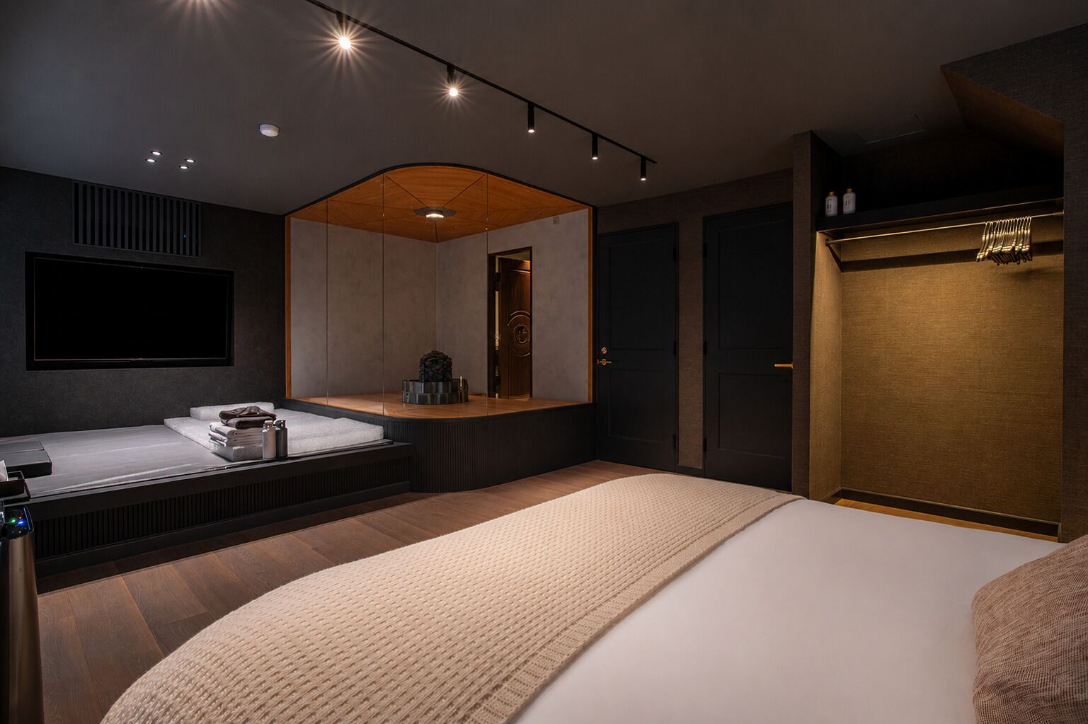 A modern bedroom with a large bed, a built-in vanity, and a walk-in closet.