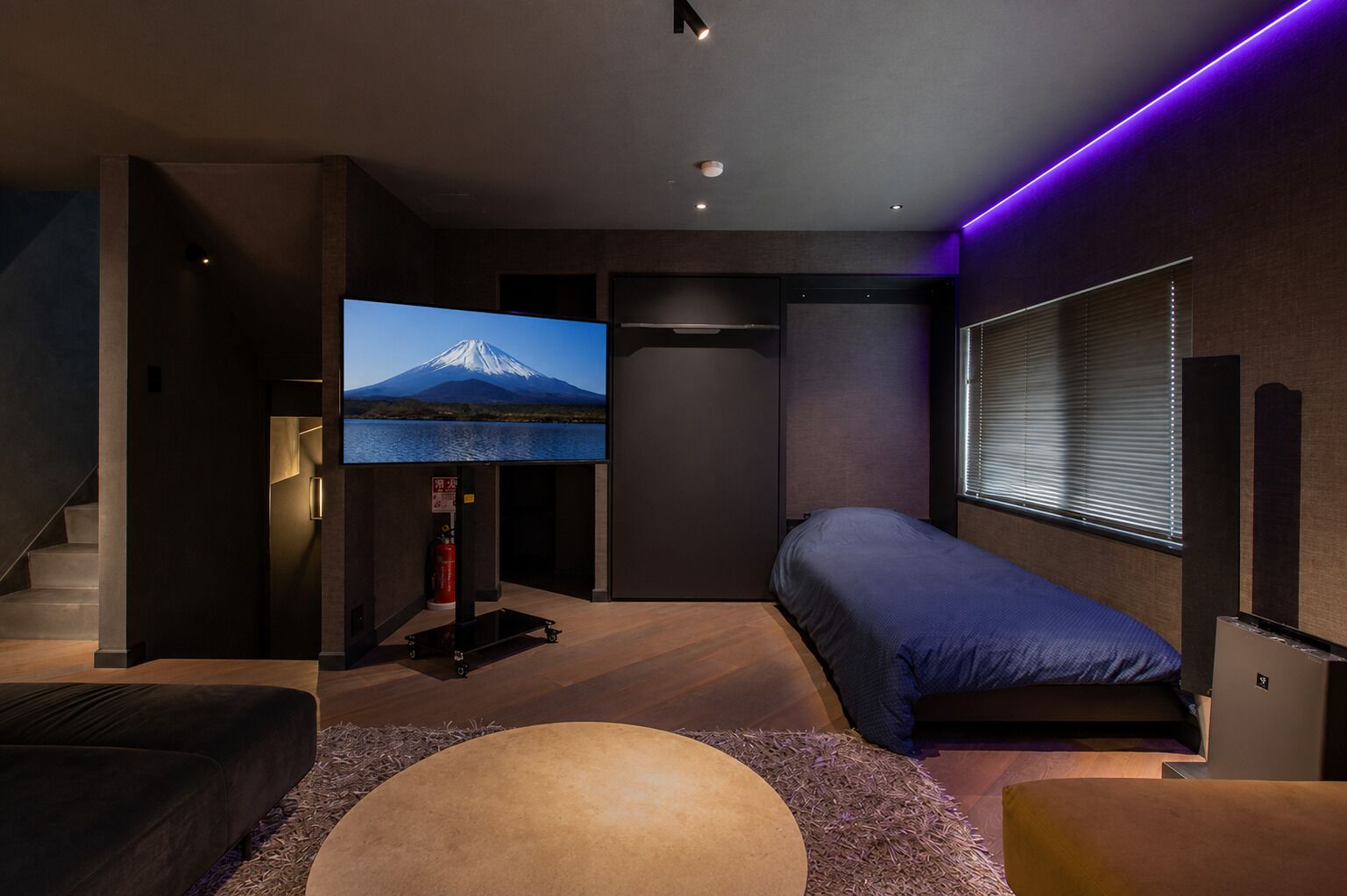 A modern bedroom with a bed, a TV, and a window.