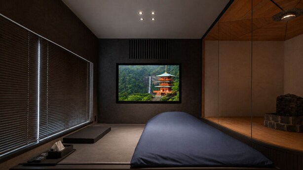 A modern bedroom with a large window, a bed, and a small seating area.