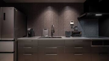 A modern kitchen with a built-in refrigerator, a coffee machine, a kettle, and a stove.