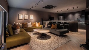 A modern living room with a sectional sofa, a round coffee table, and a kitchen area with a dining set.