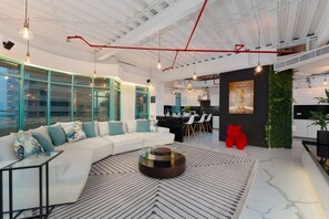 A modern interior with a curved white sofa, a round coffee table, and a dining area with white chairs. - Stunning Open-Concept 3 Bedrooms (Dubai)