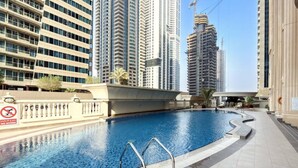 A swimming pool with a no diving sign, surrounded by high-rise buildings. - Stunning Open-Concept 3 Bedrooms (Dubai)