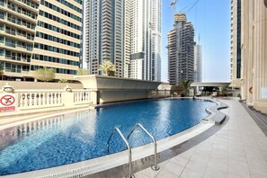 Uma piscina com placa de proibição de mergulho, cercada por edifícios altos.