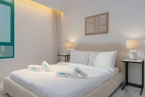 Quarto de hotel com cama, duas mesas de cabeceira, uma janela e uma obra de arte na parede.