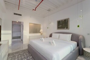 A modern hotel room with a large bed, a bedside table, a mirror, and a painting on the wall. - Stunning Open-Concept 3 Bedrooms (Dubai)
