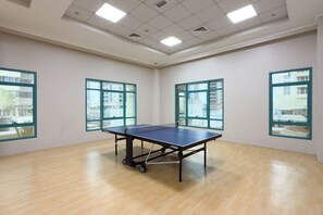 A room with a ping pong table, large windows, and a wooden floor. - Stunning Open-Concept 3 Bedrooms (Dubai)