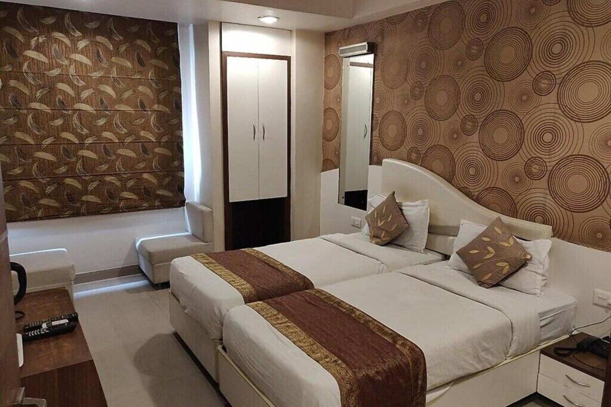 Habitación de hotel con una cama grande, un armario, un espejo y un papel tapiz estampado.