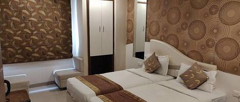Habitación de hotel con una cama grande, un armario, un espejo y un papel tapiz estampado.