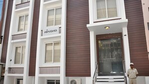 L’entrée d’un hôtel, avec une enseigne indiquant « Miravana », un escalier menant à l’entrée, et une personne se tenant au bas de l’escalier.
