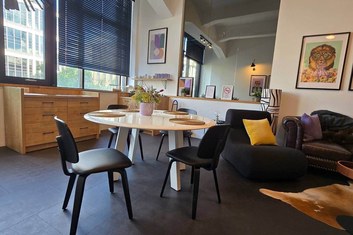 Ein zeitgemäßer Wohnraum mit Essbereich, einer Couch und Kunstwerken an den Wänden.