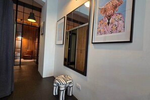 A hallway with a wooden door, a framed picture, a small stool, and a pendant light. - IMCT - Astoria Central Home 2 (Budapest)