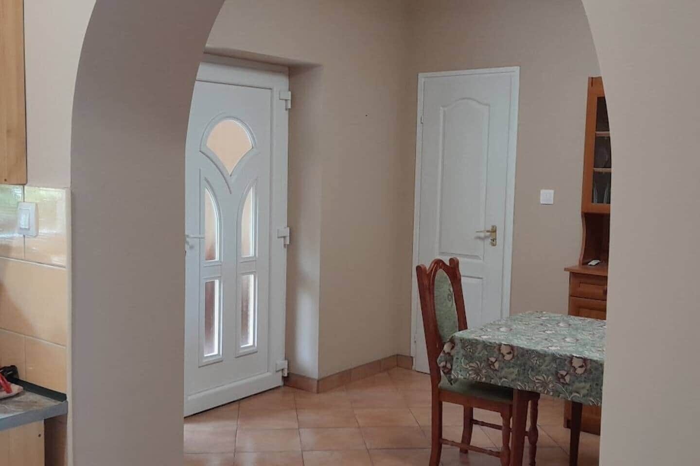 A room with a dining table, two doors, and a tiled floor.