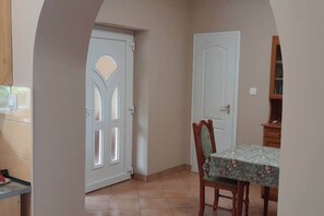 A room with a dining table, two doors, and a tiled floor.