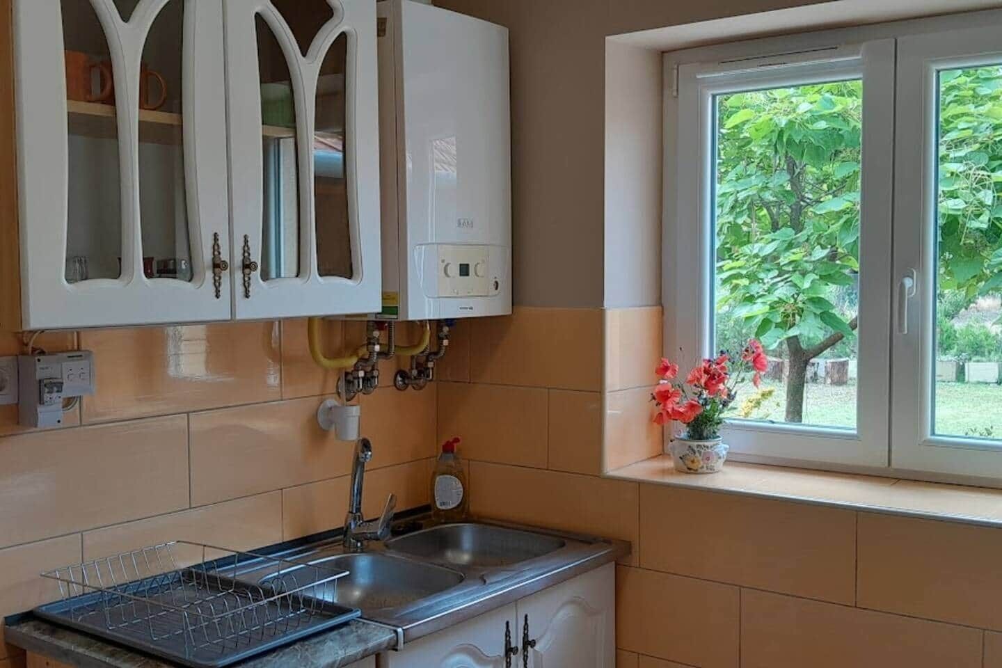 A kitchen with a built-in stove, a sink, and a window with a view of greenery.